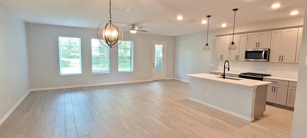 a large kitchen with granite countertop a stove a sink a window and wooden floor