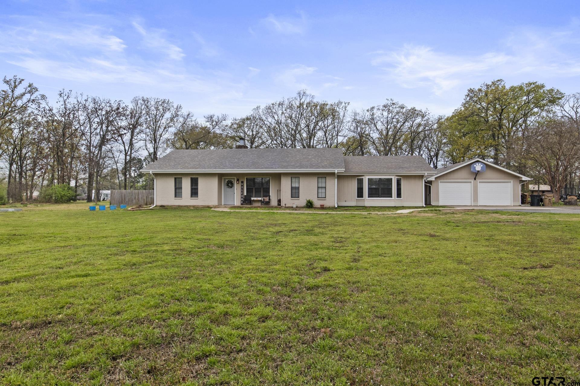 a front view of house with yard and trees in the background