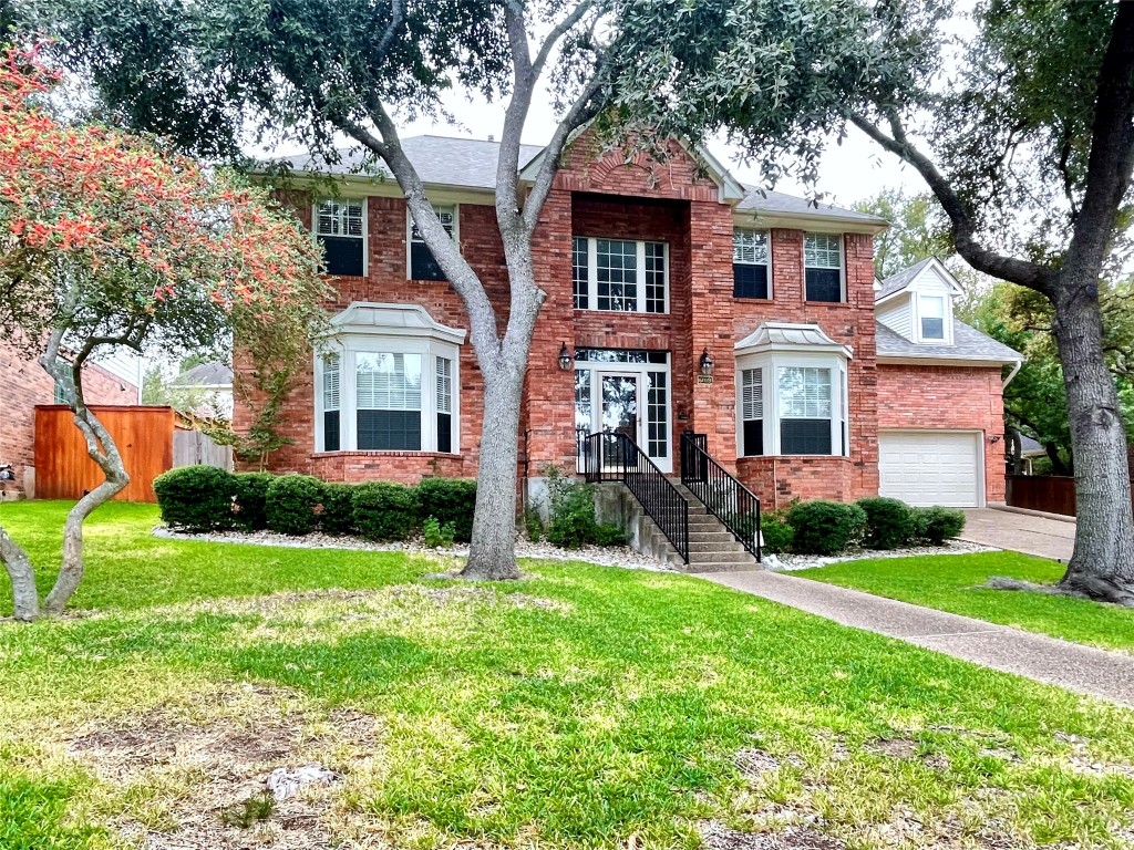 a front view of a house with garden and trees