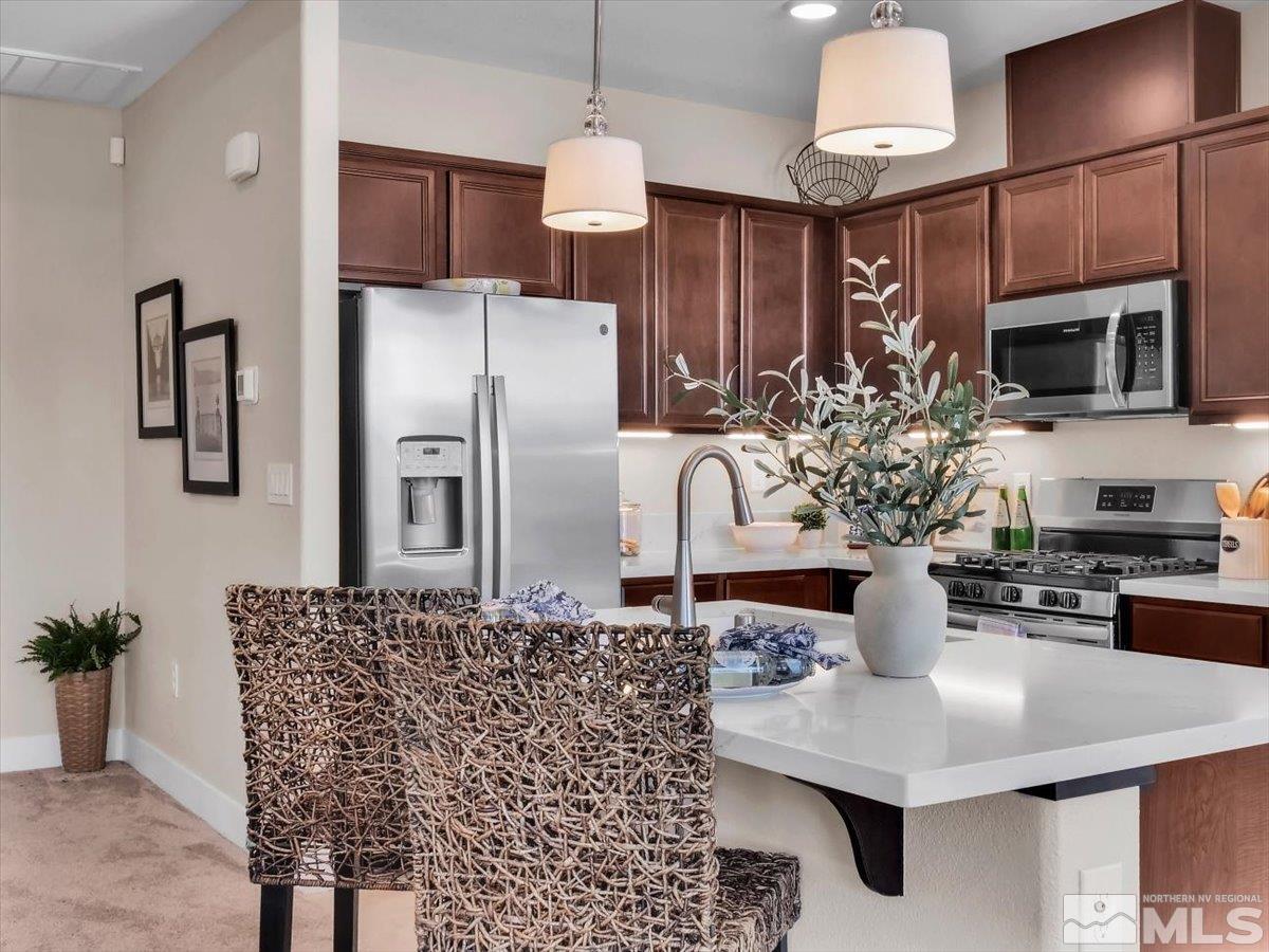 a kitchen with stainless steel appliances kitchen island granite countertop a refrigerator a stove a microwave oven a sink with a dining table and chairs