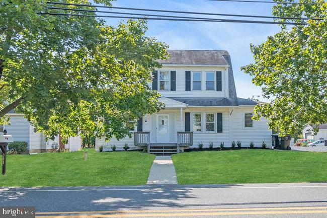 a view of a house with a yard plants and large tree