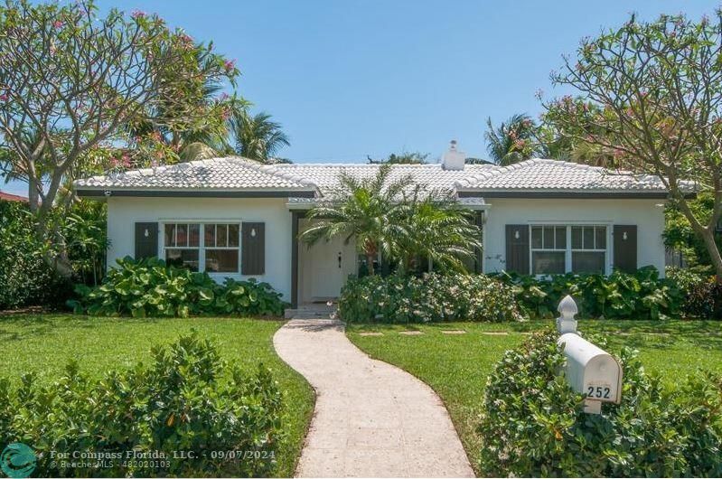 a front view of a house with a yard and potted plants