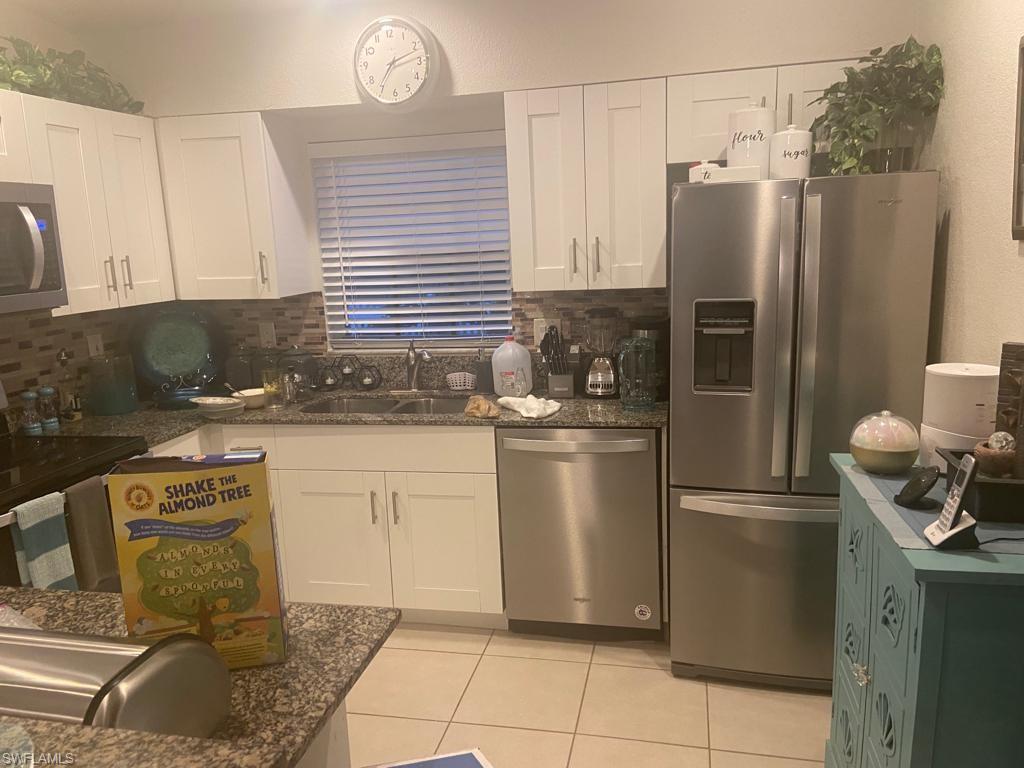 Kitchen featuring white cabinets, stainless steel appliances, sink, and backsplash