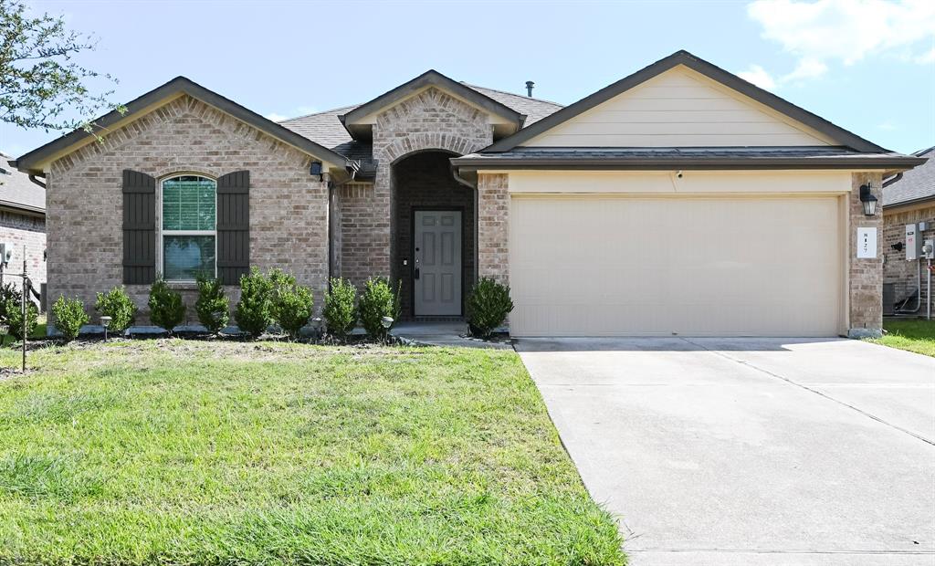 This is a single-story brick home featuring a two-car garage, a neatly manicured lawn with sprinkler system.