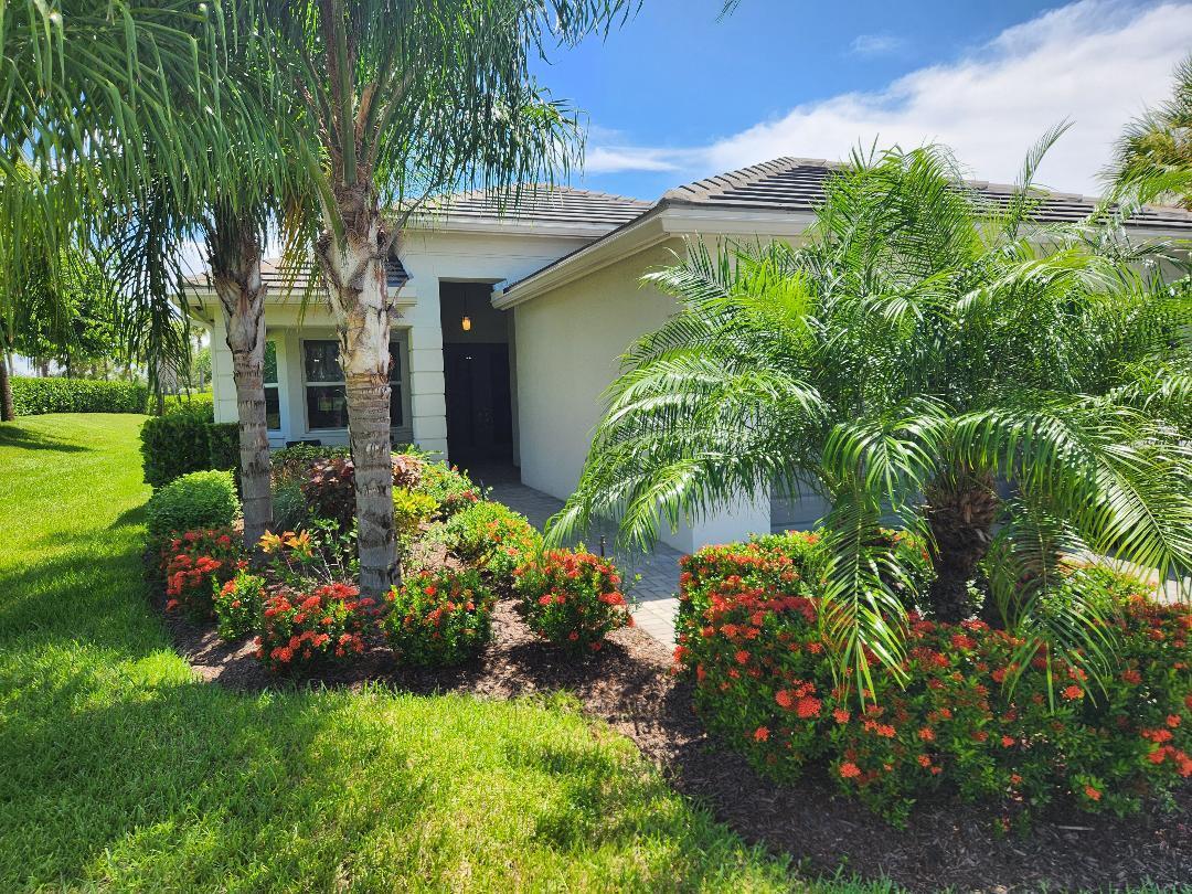 a view of a house with a big yard and flower plants