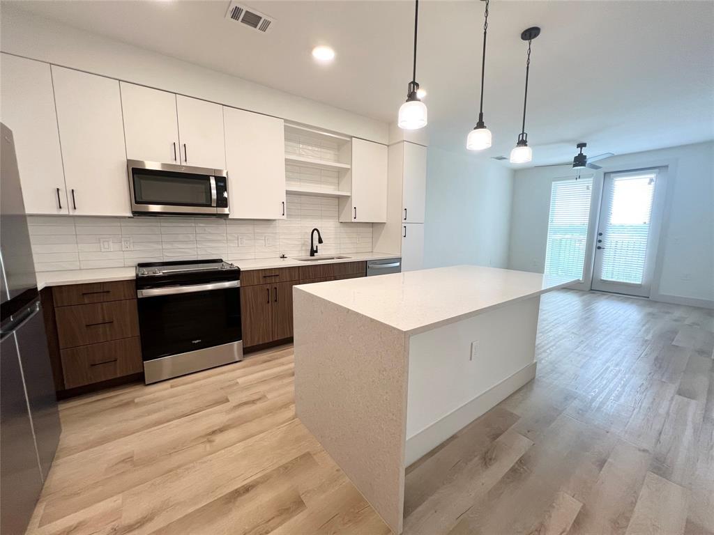 a kitchen with a sink a counter top space stainless steel appliances and cabinets