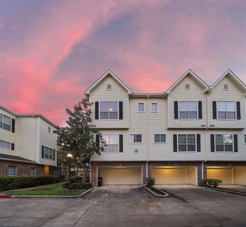 Three-story townhouse with peaked roofs and a light exterior, complete with attached garages.