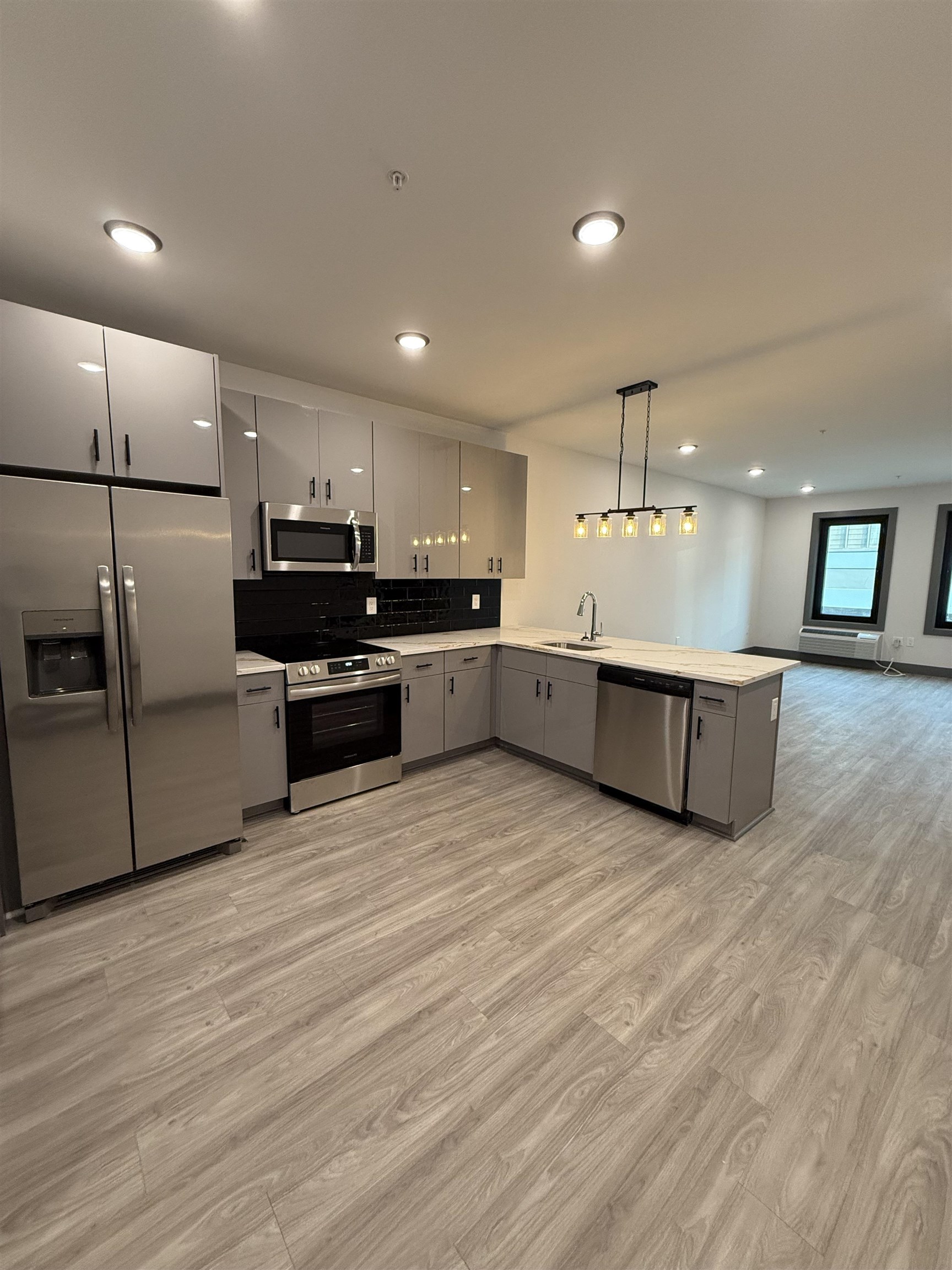 a large kitchen with a large counter top stainless steel appliances and wooden floor