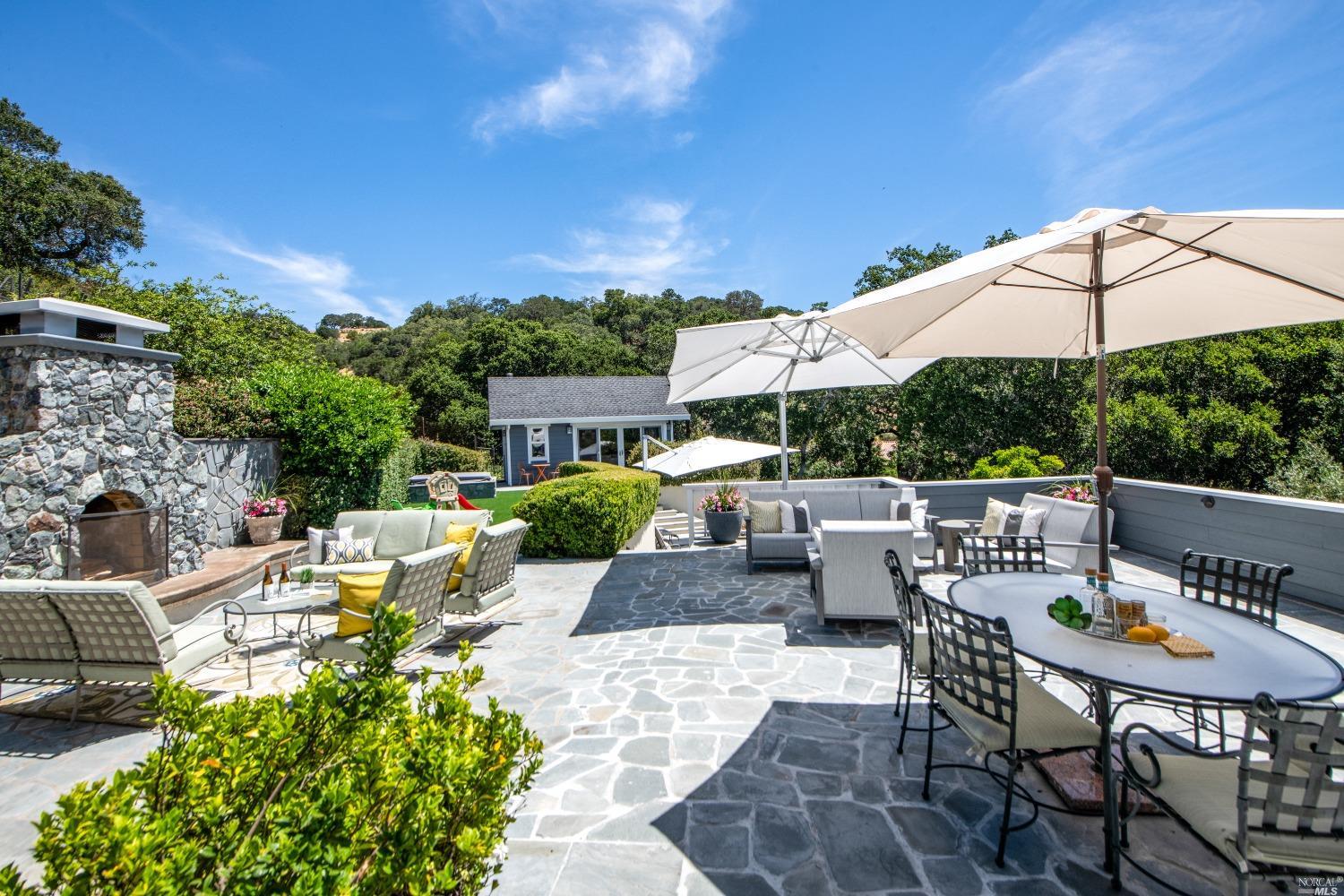 a view of a patio with couches table and chairs under an umbrella with a barbeque grill and couches