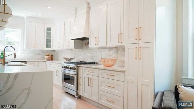 a kitchen with stainless steel appliances granite countertop a stove a sink and white cabinets