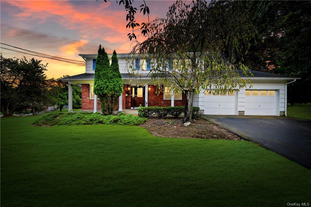 View of front of house featuring covered porch, a yard, and a garage