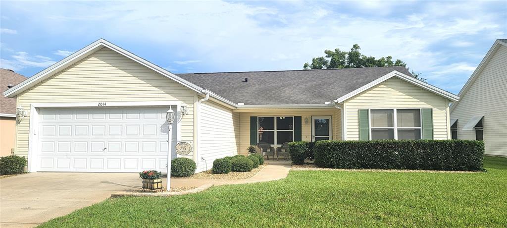 a front view of a house with a yard and potted plants