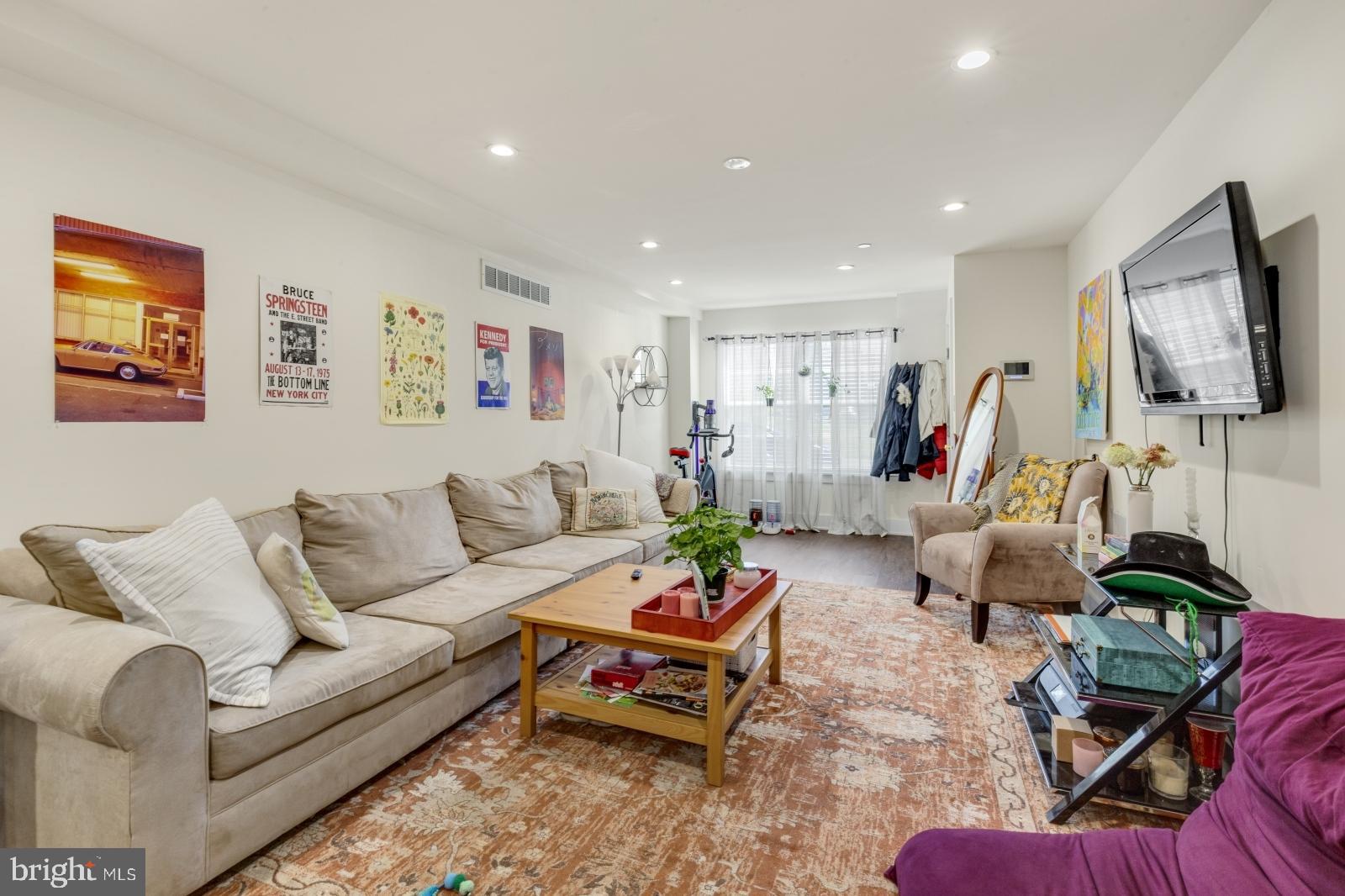 a living room with furniture a flat screen tv and a window