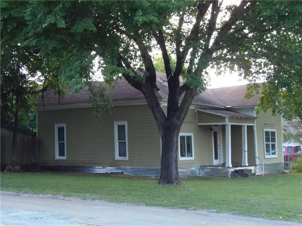 a front view of a house with a garden and trees