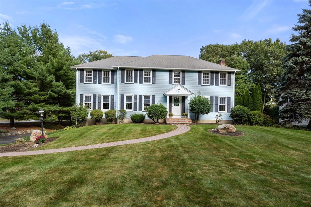 a front view of a house with garden and trees