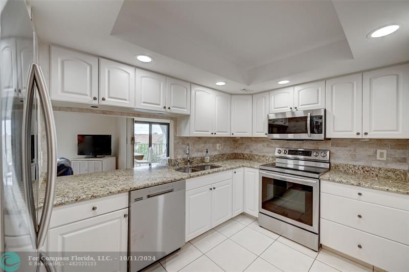 a kitchen with granite countertop stainless steel appliances white cabinets and a sink