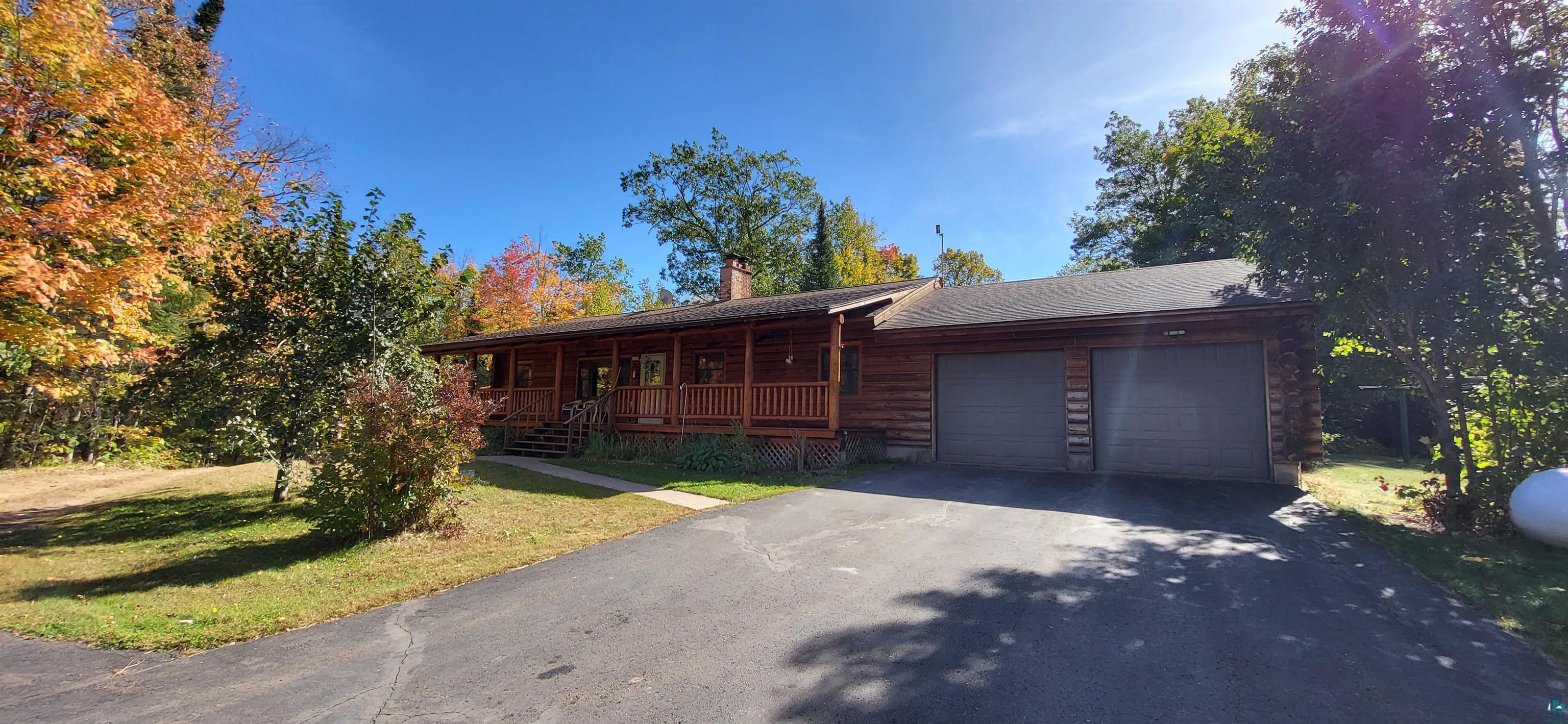 Log-style house with a front yard, a garage, and a porch