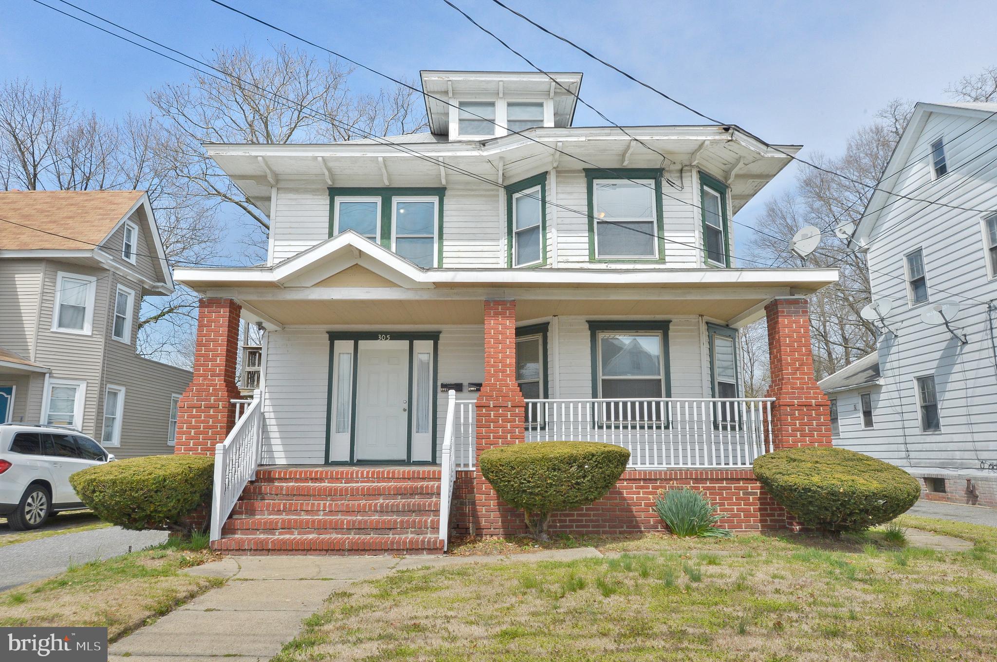 a front view of a house with a yard and potted plants