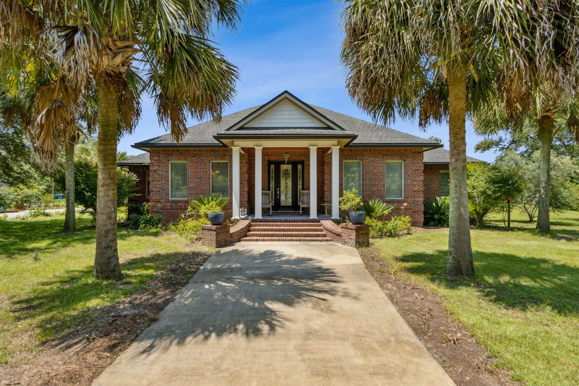 a view of a house with a yard and palm trees