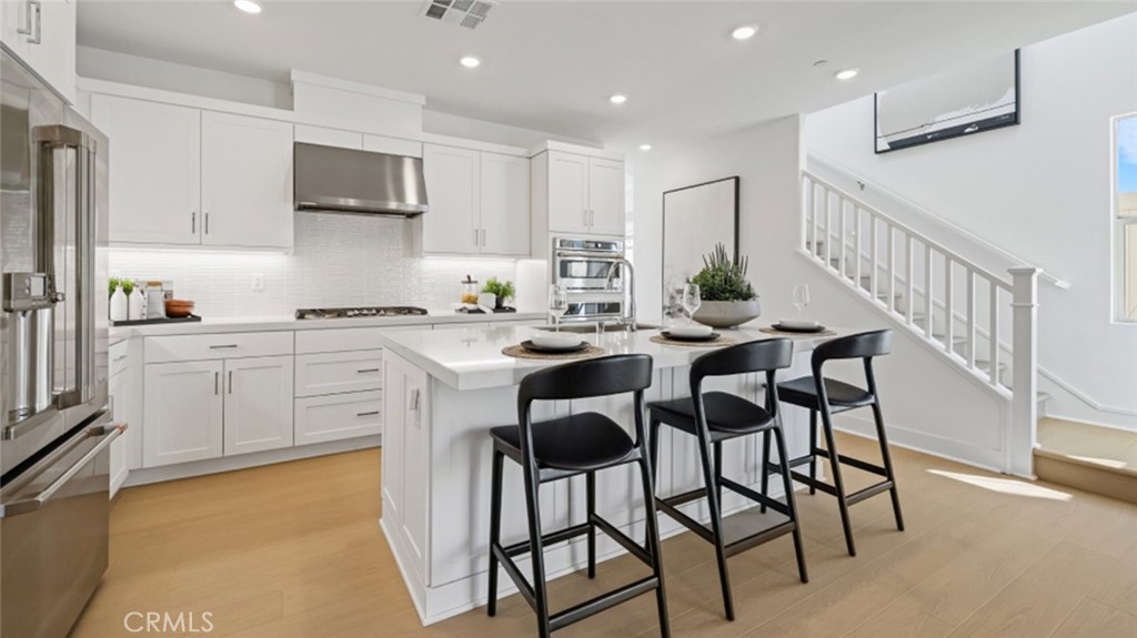 a kitchen with stainless steel appliances kitchen island granite countertop a table chairs sink and cabinets