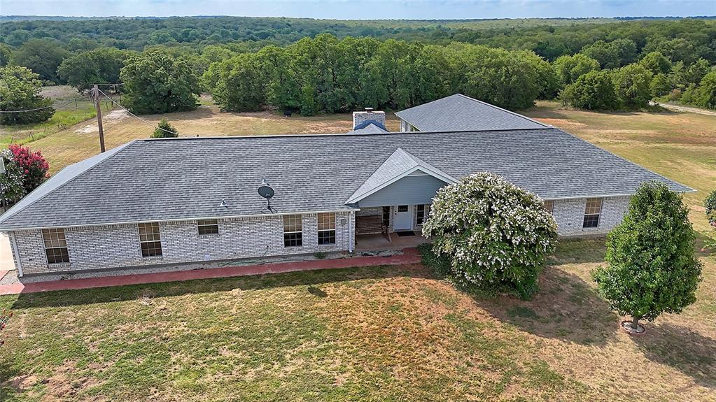 an aerial view of a house with swimming pool and large trees