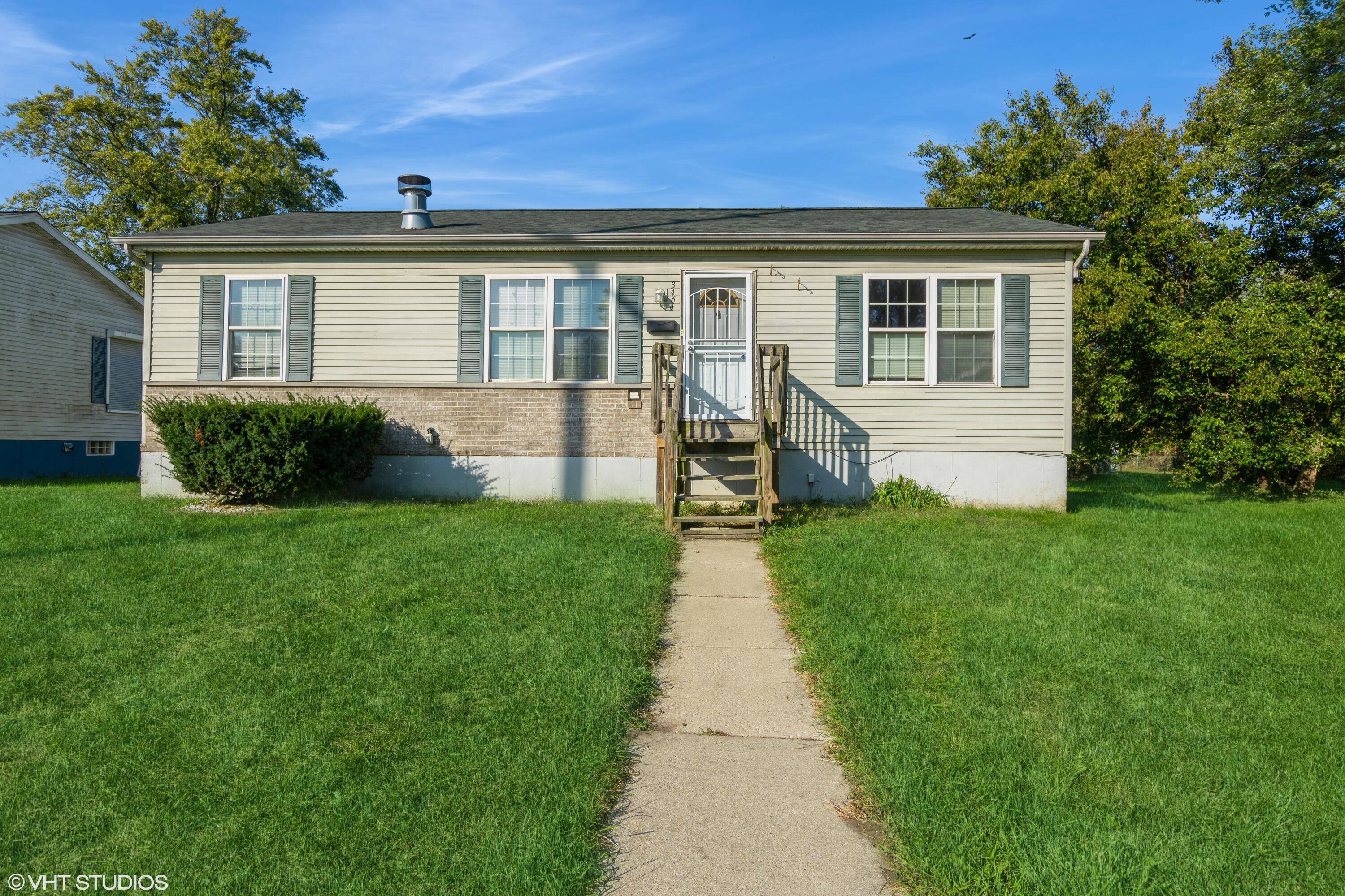 a front view of a house with a yard and green space