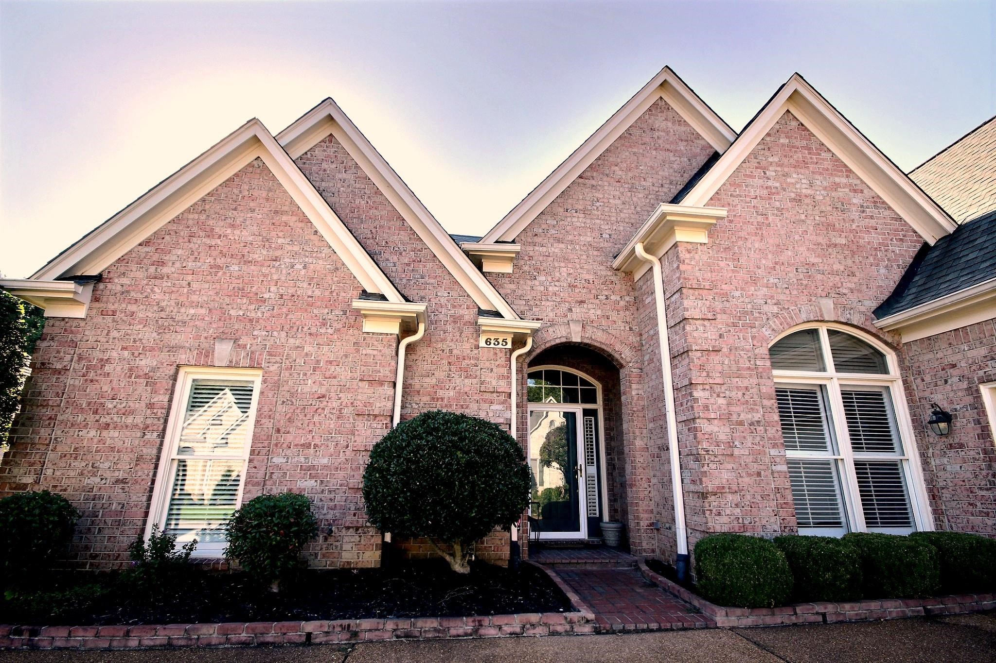 a view of a brick house with many windows and a yard