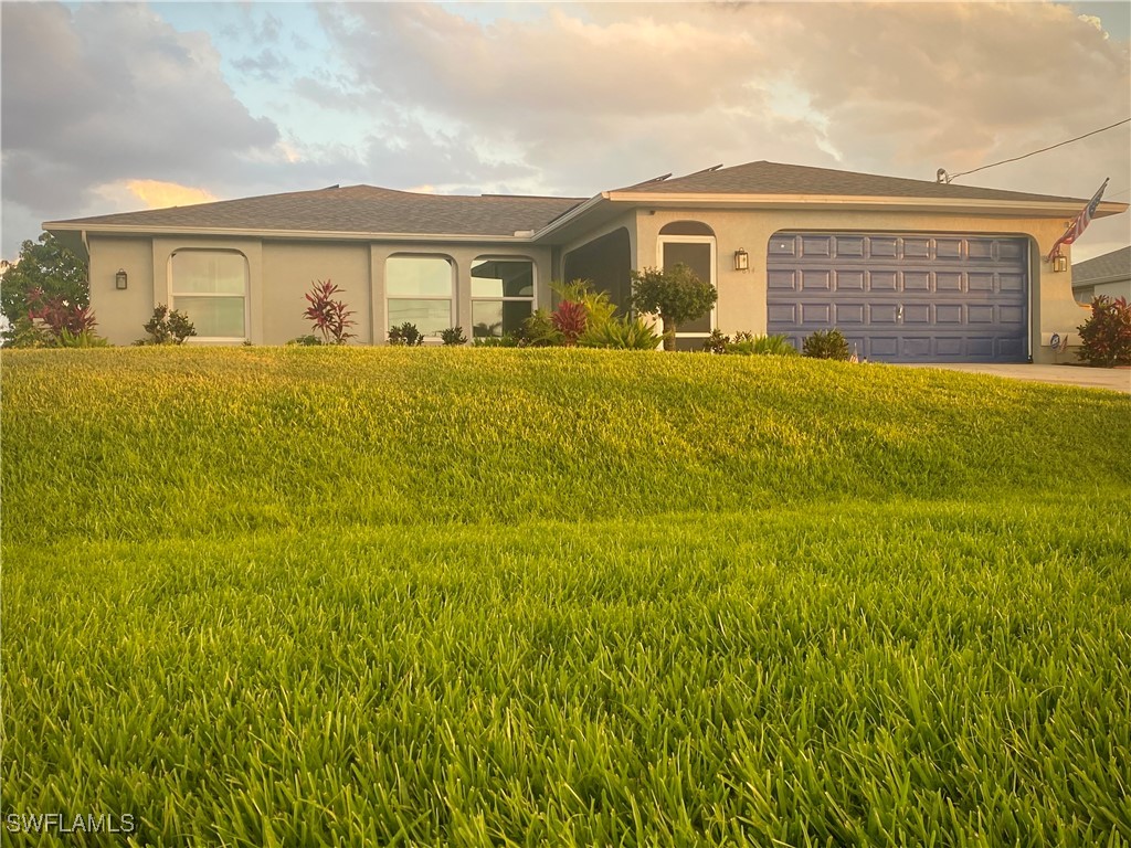 a front view of house with yard and trees in the background