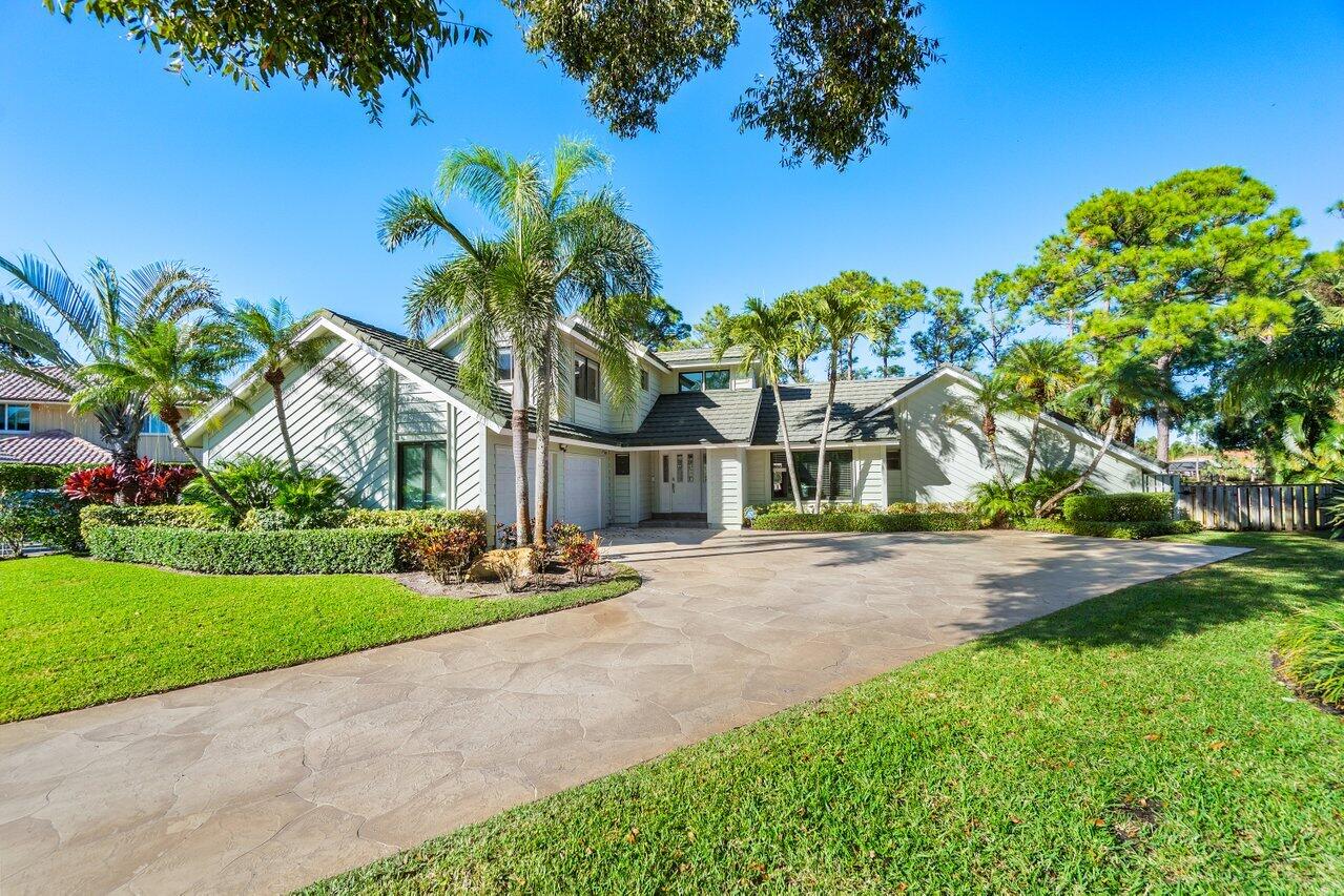 a front view of a house with a garden and tree