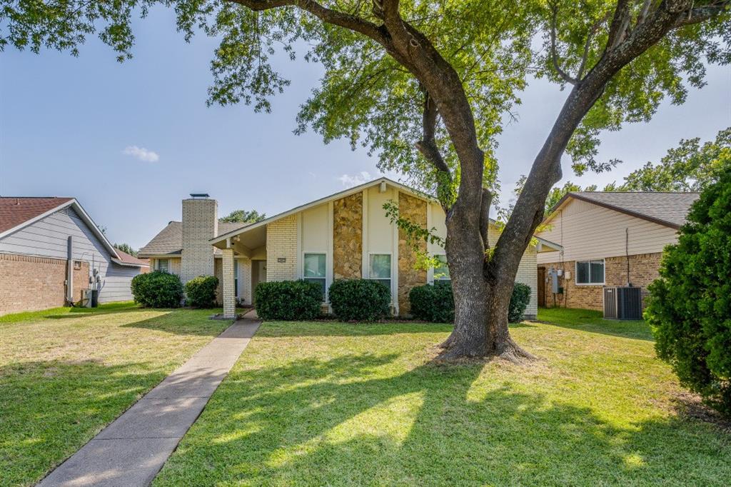 a view of a house next to a big yard and large trees