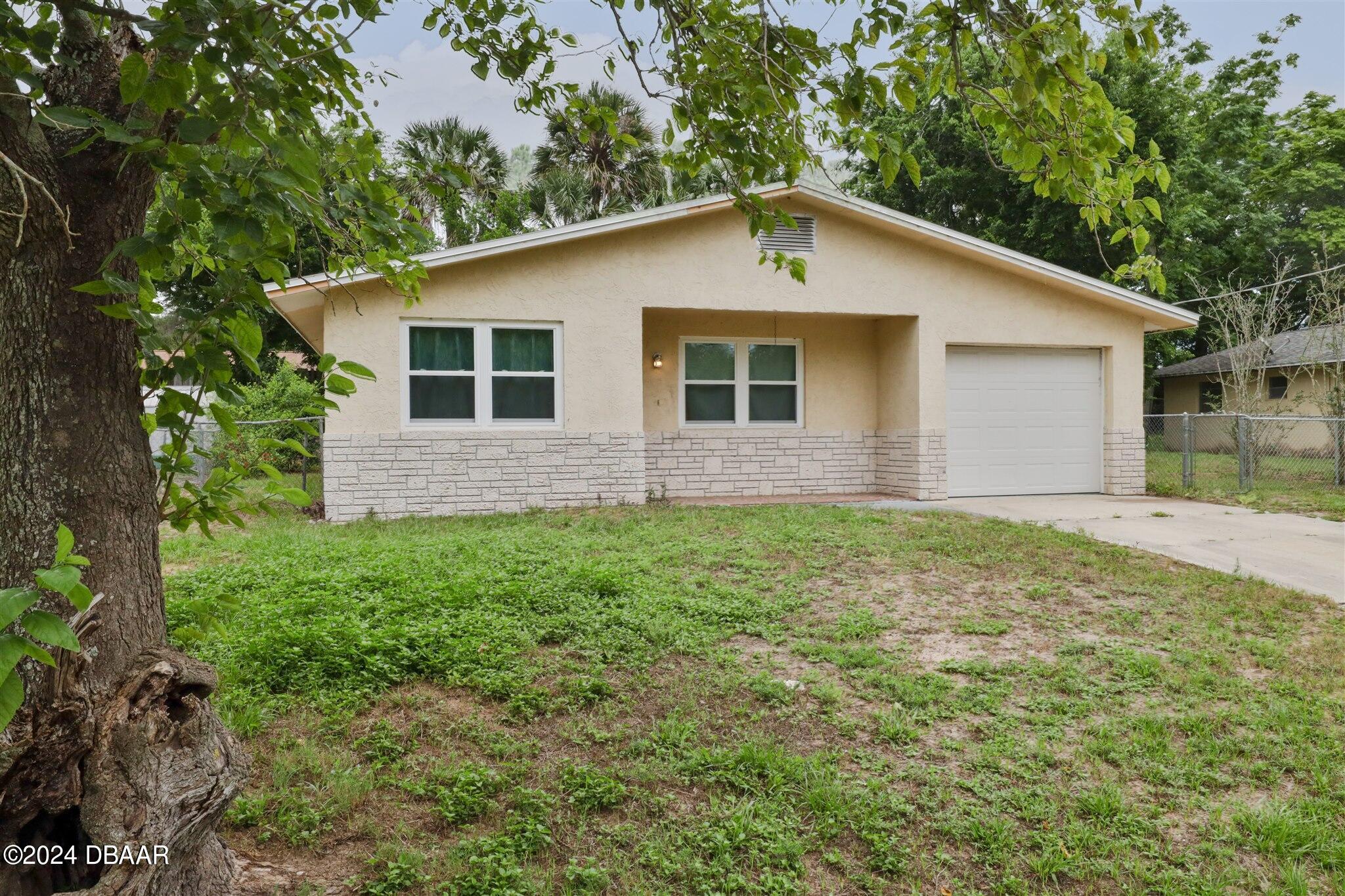 a front view of house with yard and trees all around