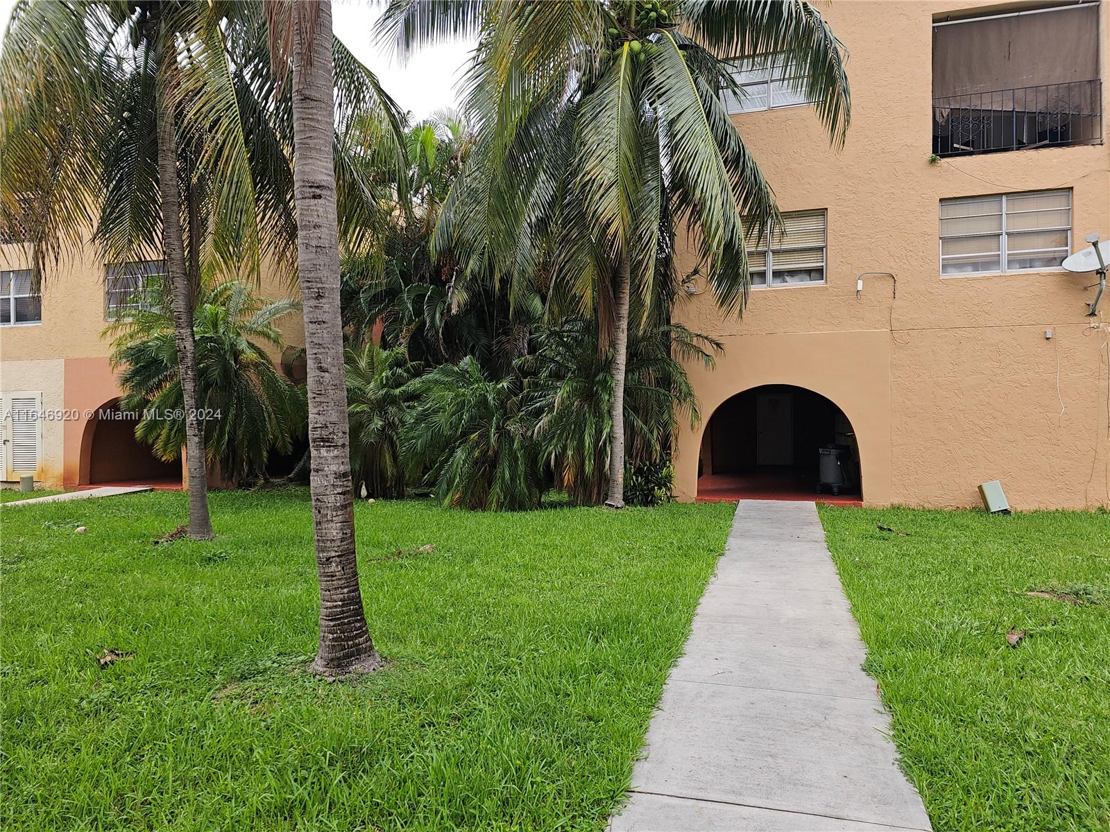 a front view of a house with a yard and palm trees