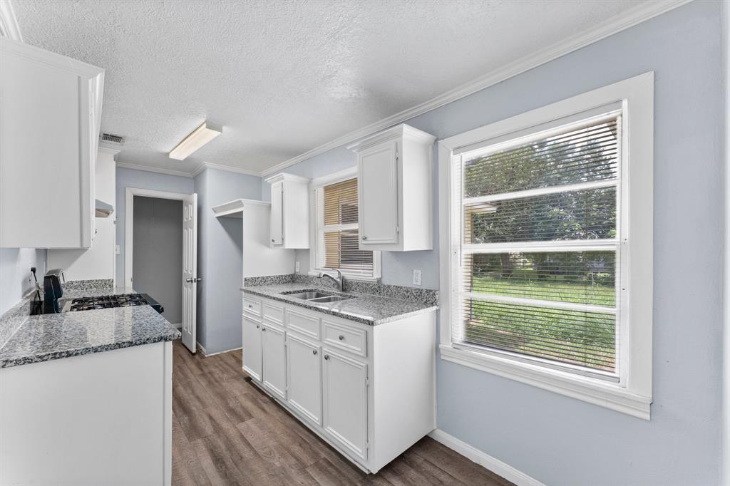 a kitchen with granite countertop a sink stove and cabinets