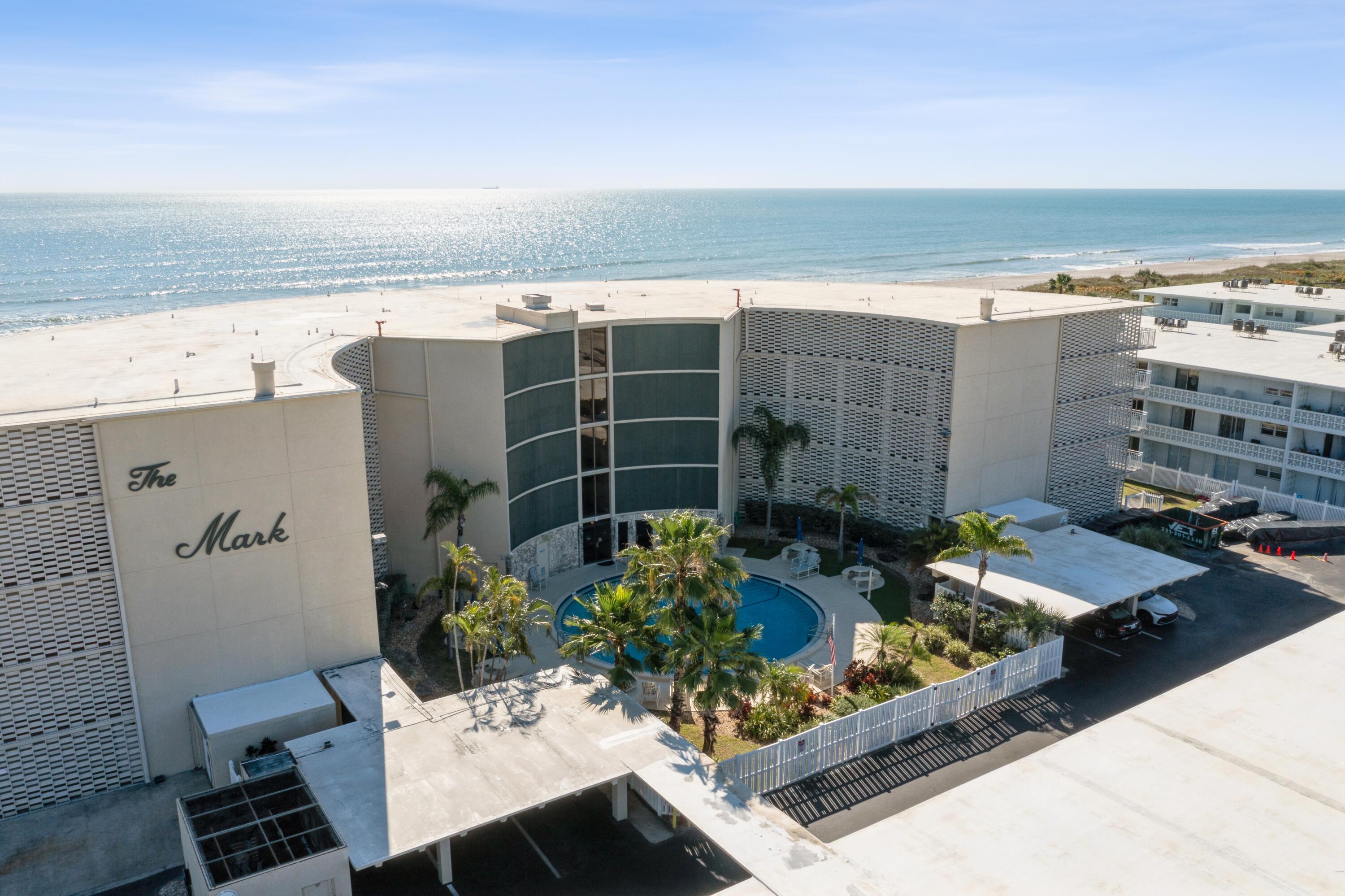 a view of a patio with lawn chairs potted plants and ocean view