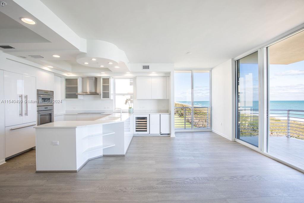 a large kitchen with kitchen island a sink wooden floor and a refrigerator