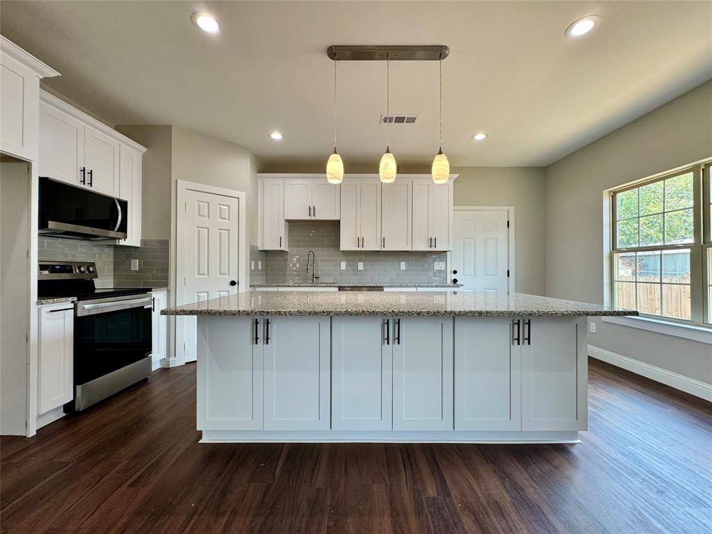 a large kitchen with cabinets wooden floor and stainless steel appliances