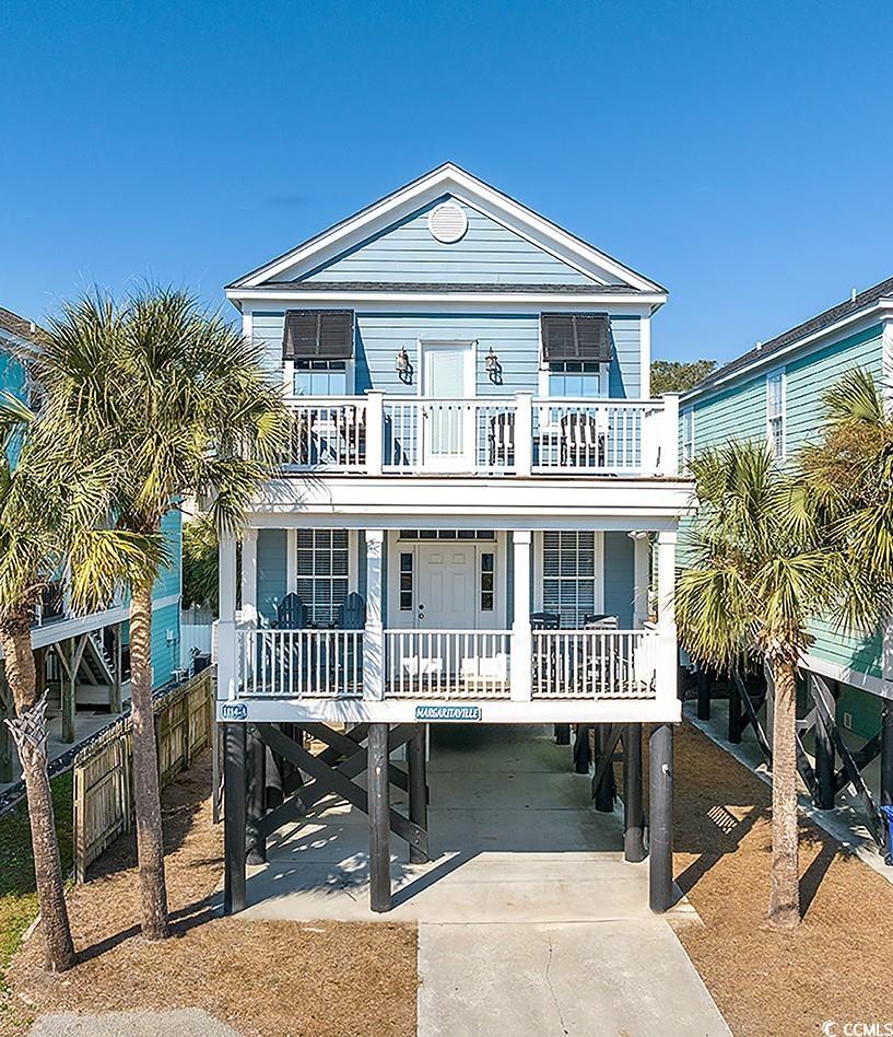 Raised beach house with a carport, a porch, and a