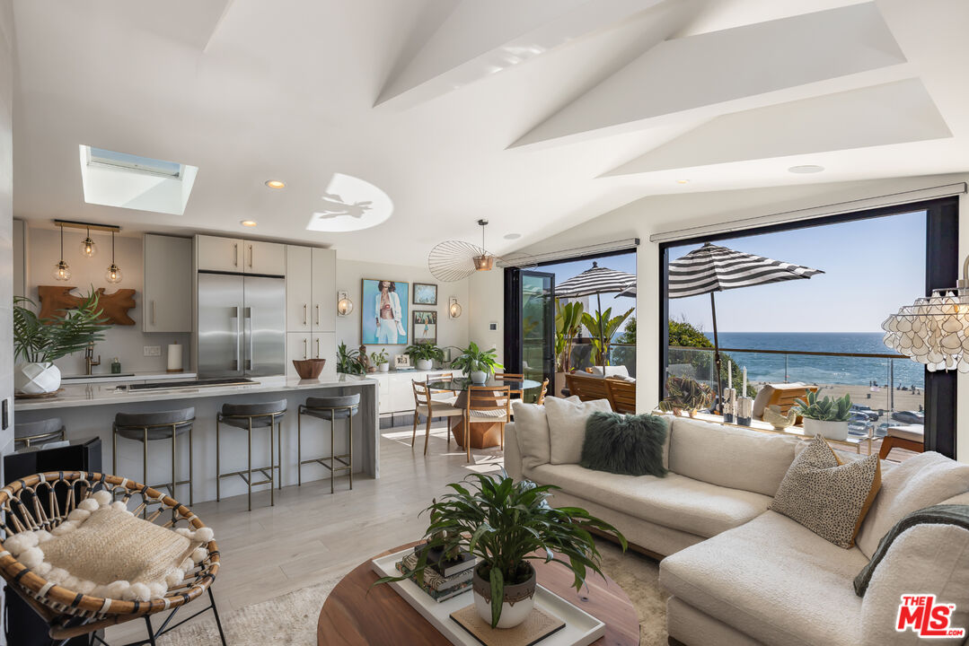 a living room with furniture kitchen view and a large window