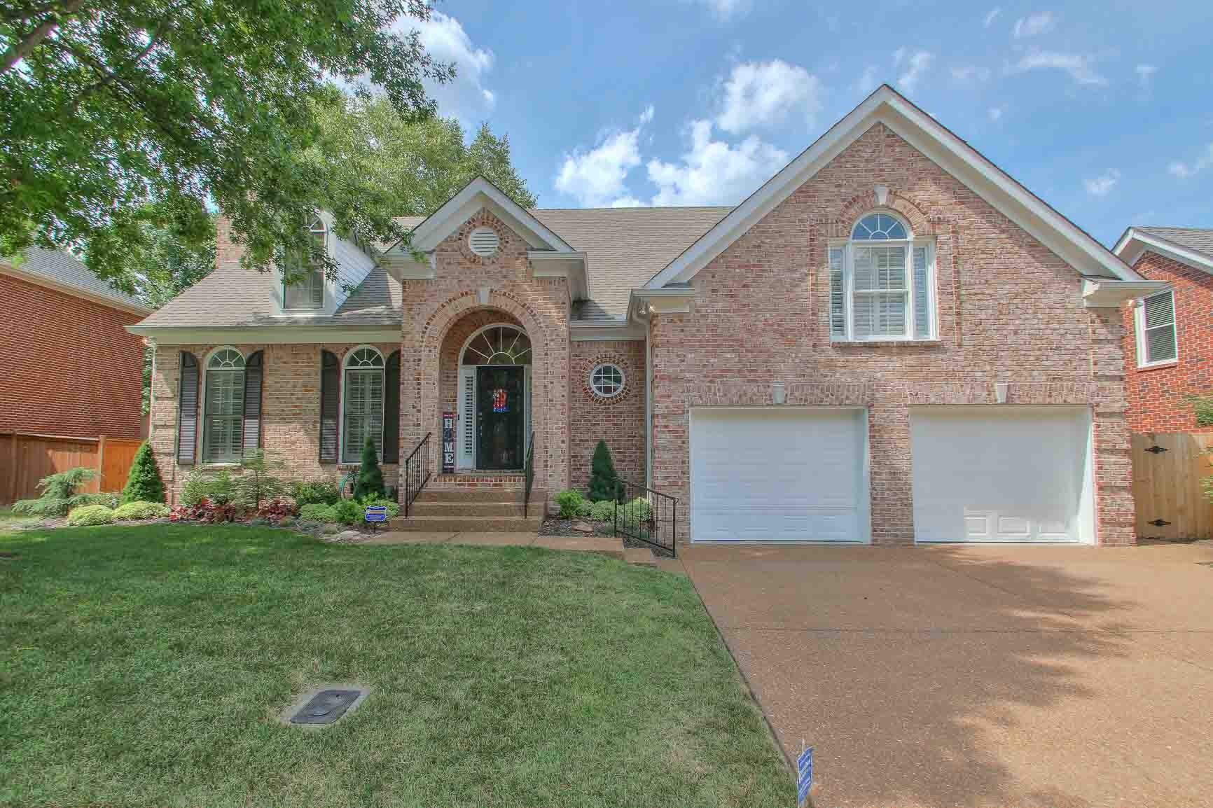 a front view of a house with a garden and yard