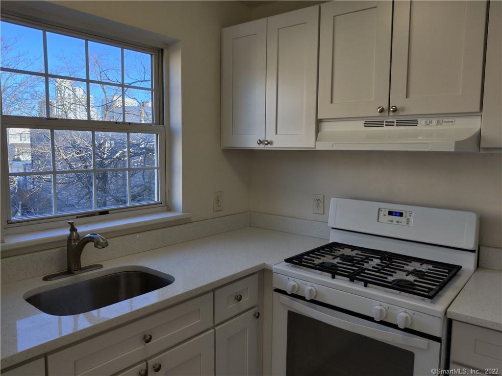 a kitchen with granite countertop white cabinets and a stove