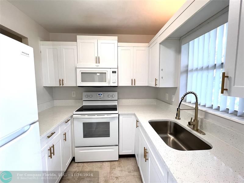 a kitchen with white cabinets sink and white appliances