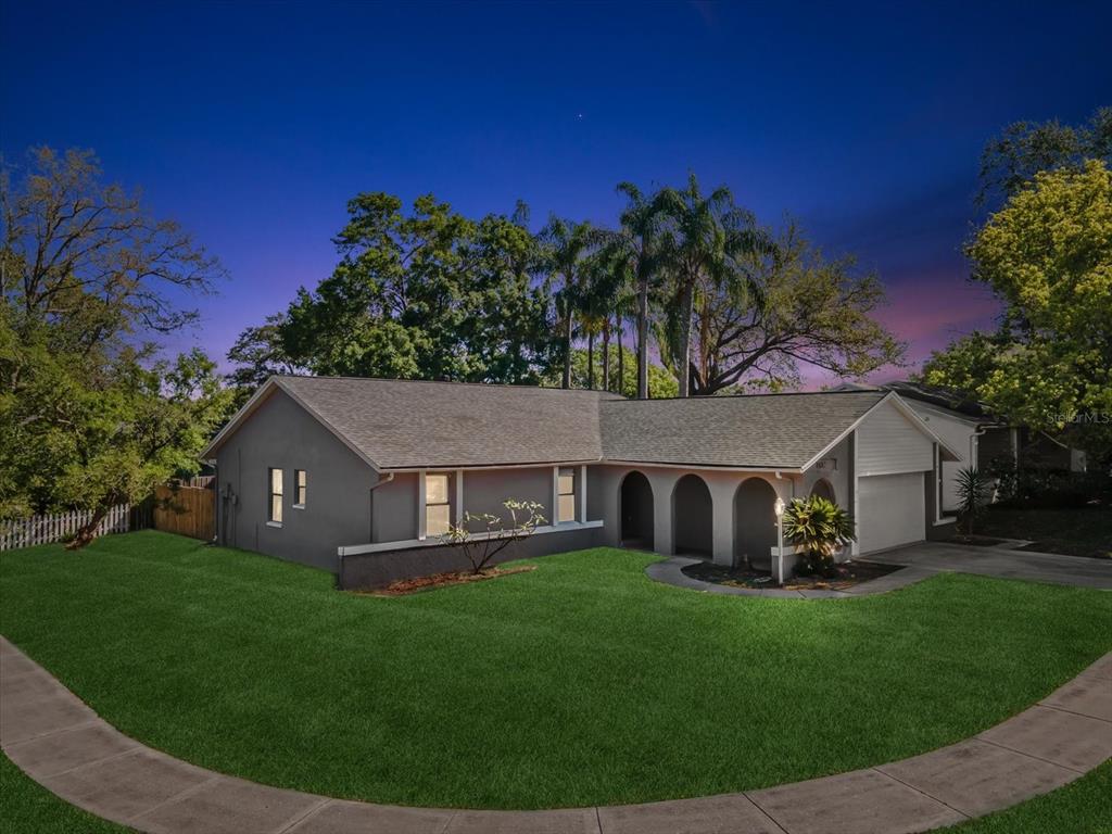 a view of a house with a yard potted plants and a bench