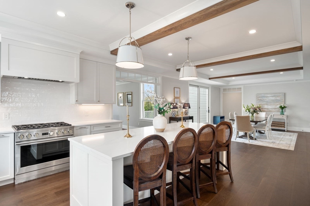 a kitchen with kitchen island a dining table chairs stainless steel appliances and cabinets