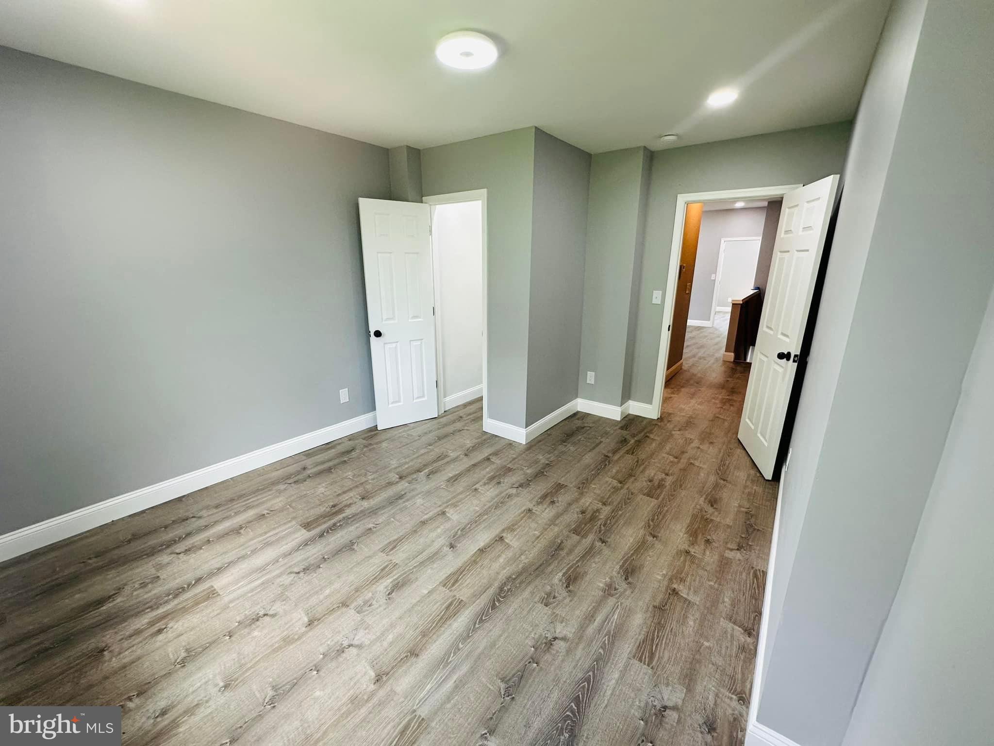 an empty room with wooden floor and mirror