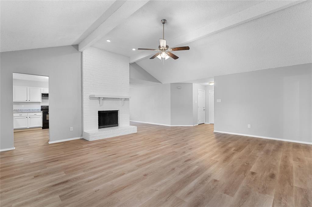 a view of empty room with wooden floor and fireplace