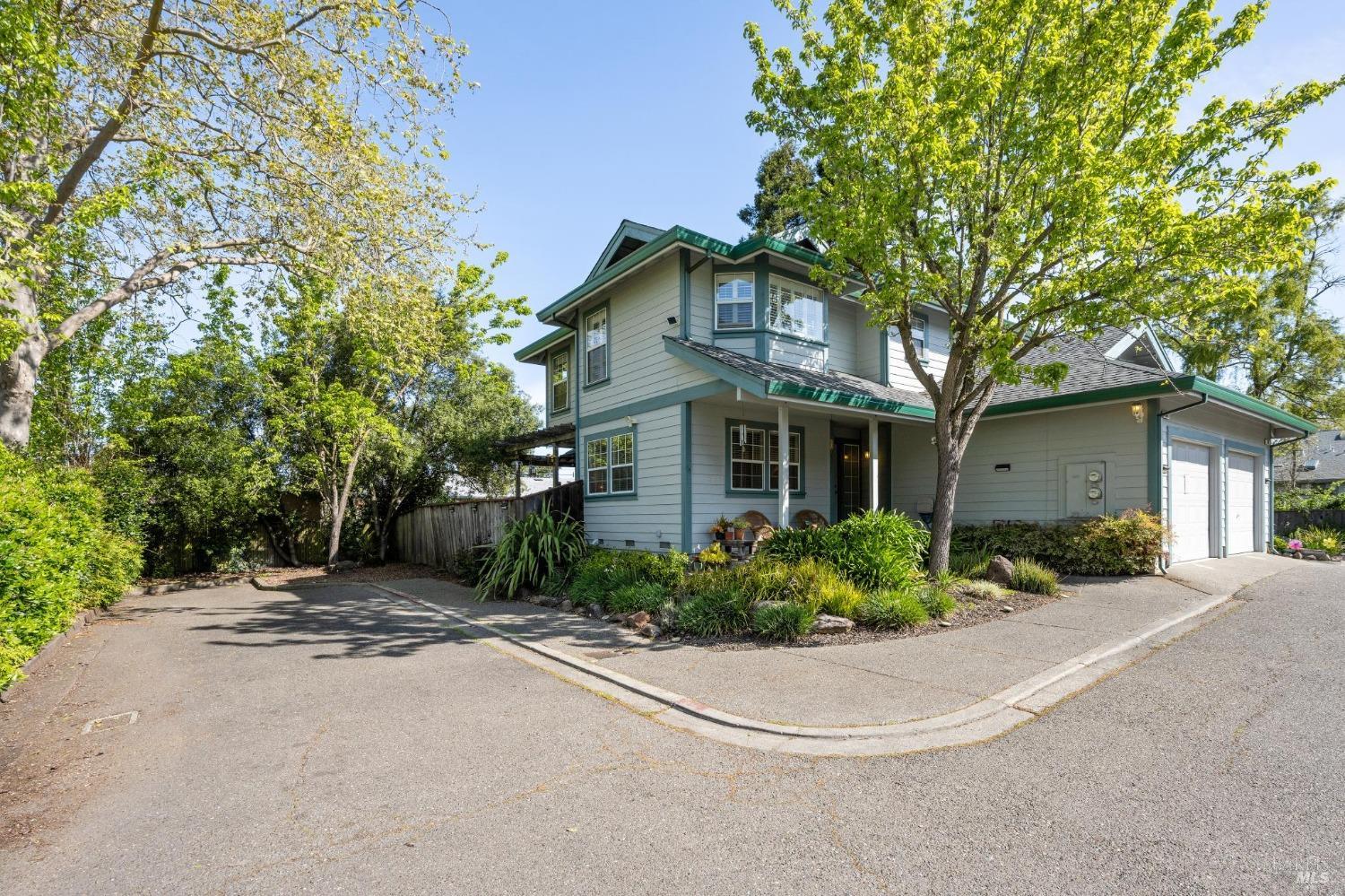 a view of a house with a small yard and large trees