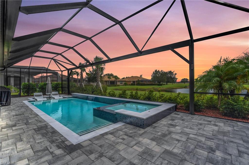 Pool at dusk featuring a water view, an in ground hot tub, pool, water feature and panoramic screen