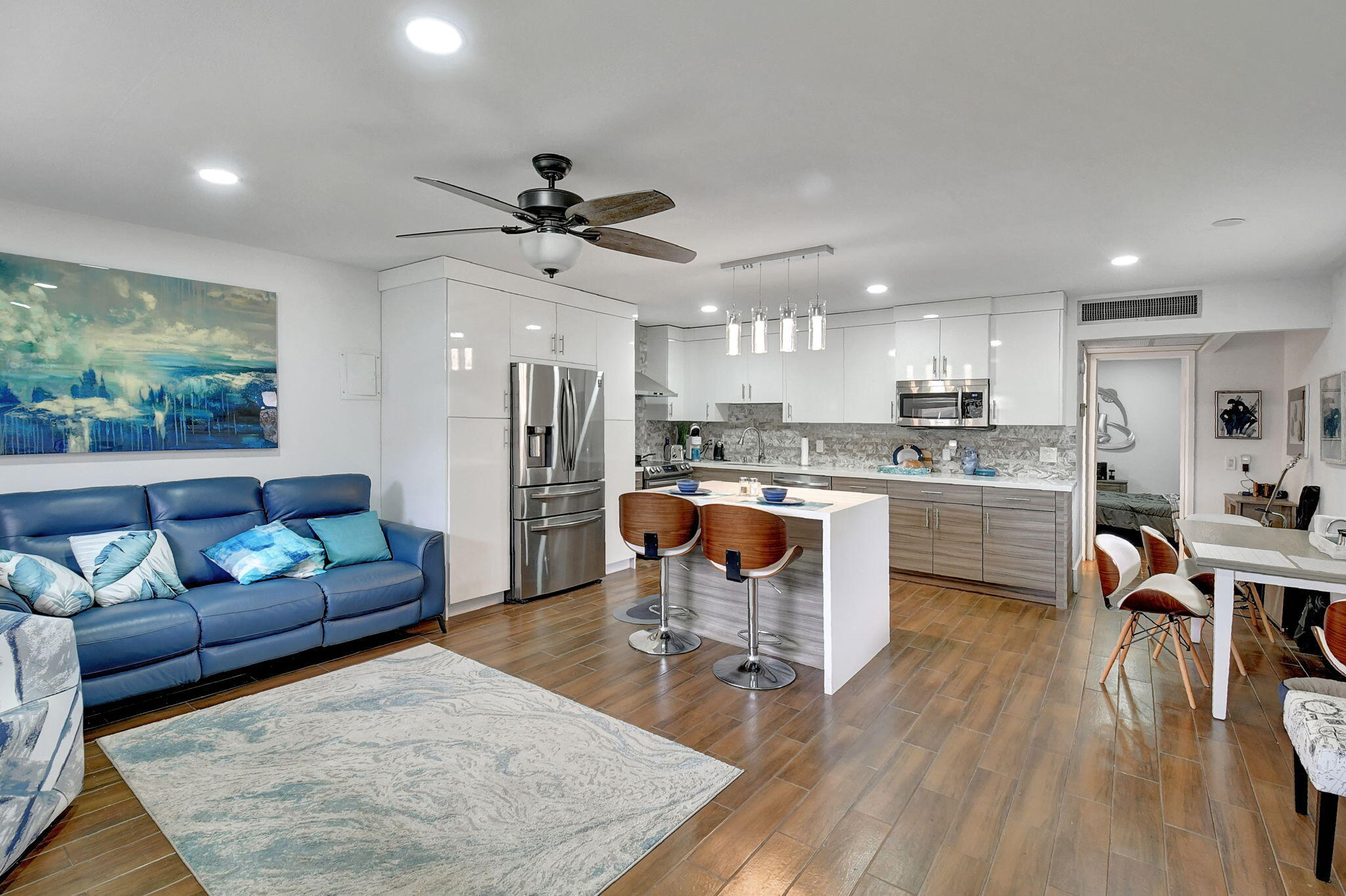 a living room with stainless steel appliances kitchen island granite countertop furniture and a wooden floor