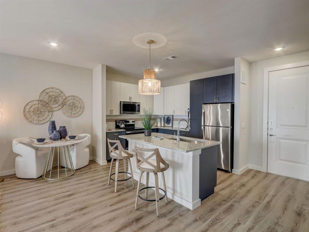 a kitchen with stainless steel appliances a dining table chairs stove and refrigerator