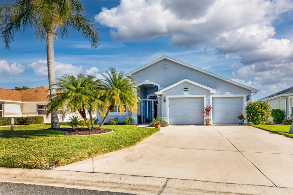 a yellow house with a yard and palm trees